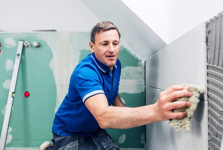 Homme qui nettoie du carrelage mural après la pose