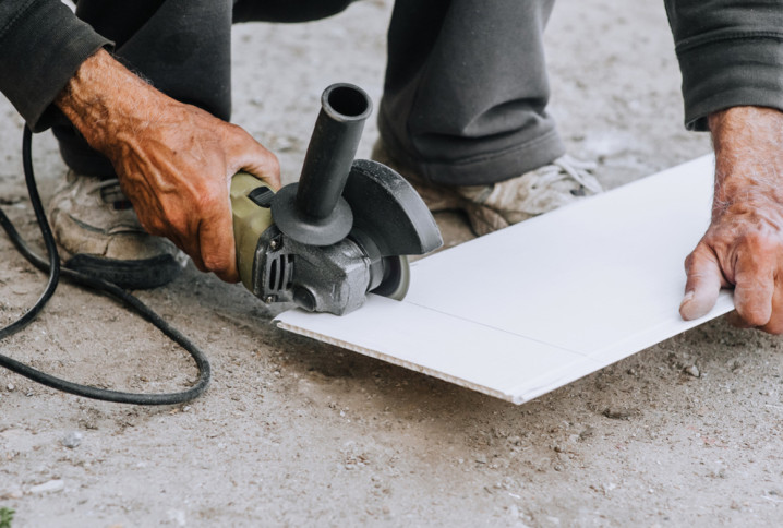 Carreleur en train de découper du carrelage blanc avec meuleuse