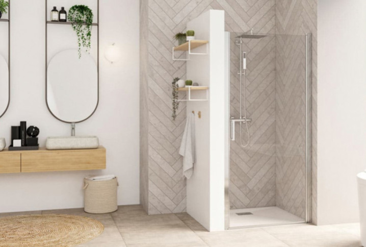 Salle de bains lumineuse avec douche équipée d’une paroi vitrée pivotante et d’un receveur blanc.