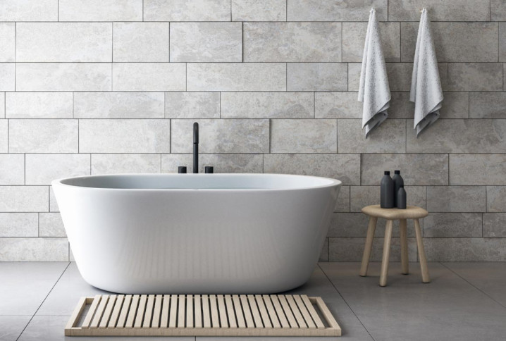 baignoire blanche avec mur à carreaux et décoration en bois