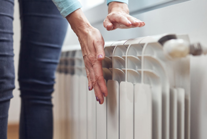 Femme qui met ses mains proche d'un radiateur pour sentir la chaleur
