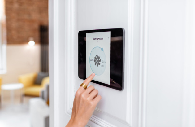 Personne qui utilise une tablette de contrôle domotique pour sa climatisation
