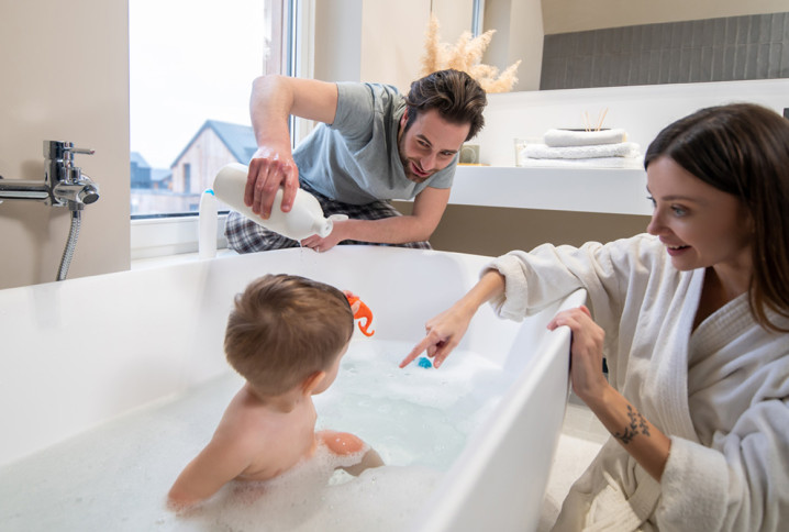 Jeune famille qui passe du bon temps dans sa salle de bains et avec la baignoire