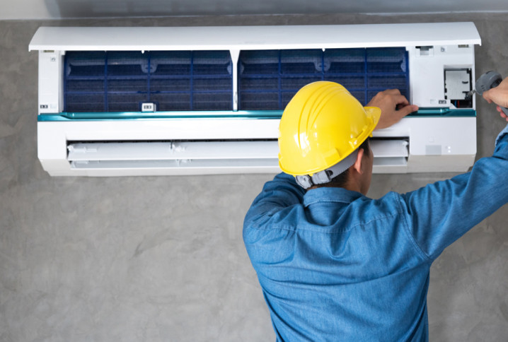 Technicien en train d’ouvrir une unité intérieure de climatisation pour réaliser l’entretien et le nettoyage du système de climatisation.