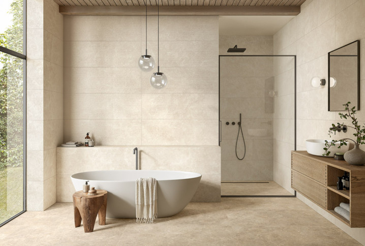 Salle de bains minimaliste avec baignoire îlot, douche à l’italienne et faïence beige grand format.