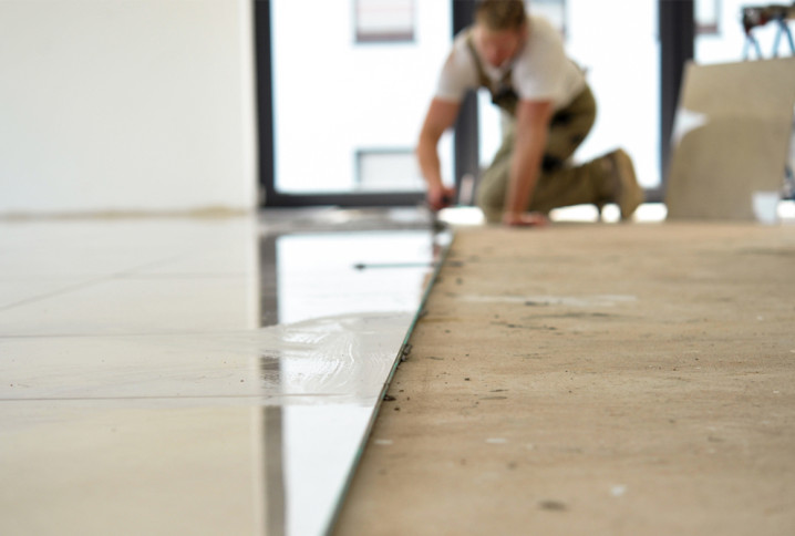 Homme qui pose des carreaux de carrelage grand format au sol