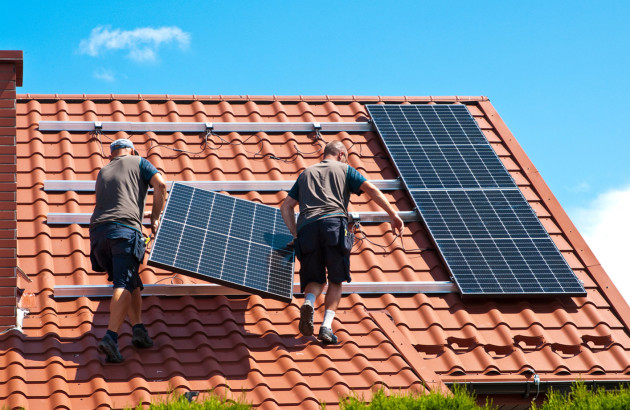 Ouvriers qui installent un panneau photovoltaïque sur un toit