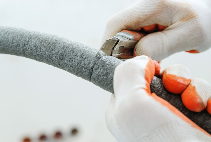 Homme avec des gants qui utilise un cutter pour découper un tuyau