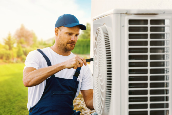 Artisan qui travaille sur une unité extérieure de climatisation
