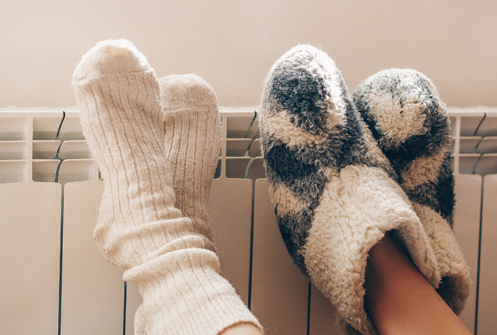 Deux personnes qui posent leurs pieds avec des chaussettes en laine contre un radiateur