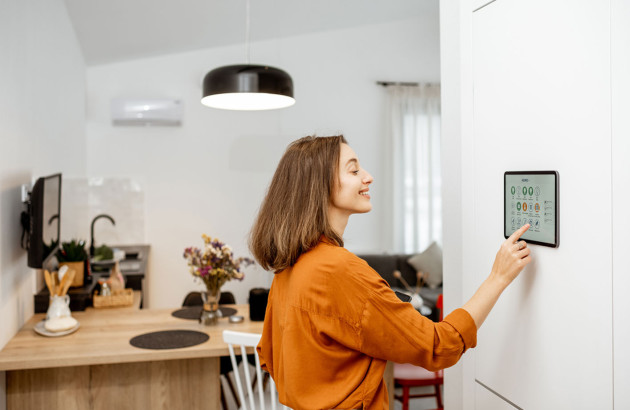Femme qui utilise un système de contrôle domotique, maison intelligente
