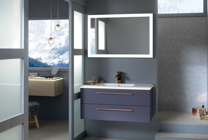 Salle de bains moderne avec meuble vasque suspendu, miroir lumineux et douche à l’italienne respectant les normes électriques.