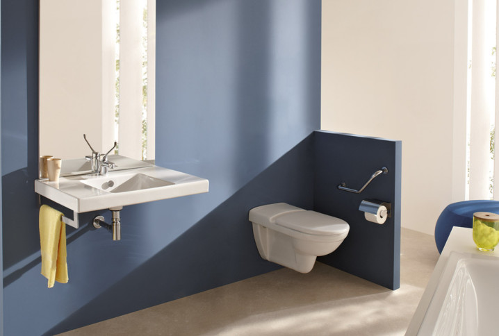 Salle de bains PMR avec lavabo suspendu et WC mural accessibles dans espace moderne.