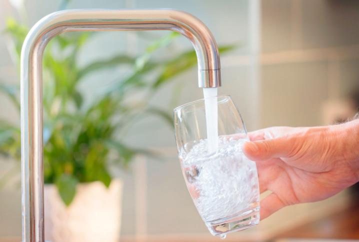 Personne qui se sert un verre d'eau à son robinet