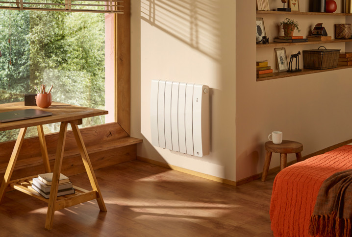 Radiateur électrique blanc positionné proche d'une fenêtre dans une chambre