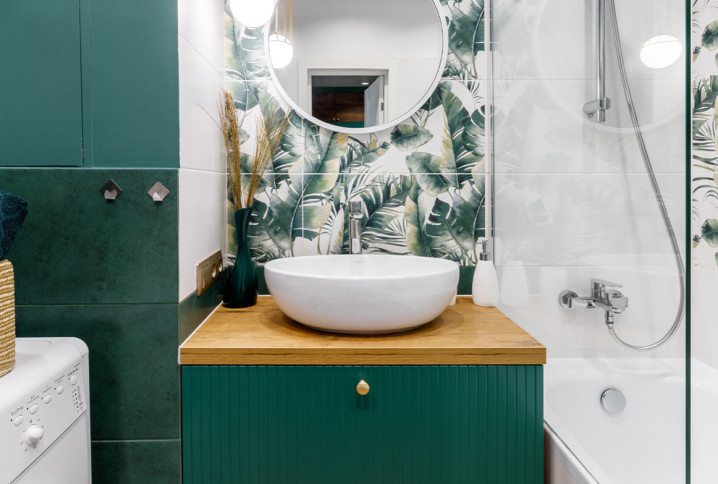 Petite salle de bains optimisée avec meuble vasque, miroir rond et carrelage végétal