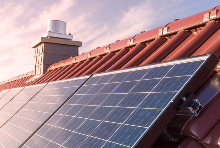 Panneaux solaires photovoltaïques installés sur une toiture en tuiles rouges, éclairés par le soleil.
