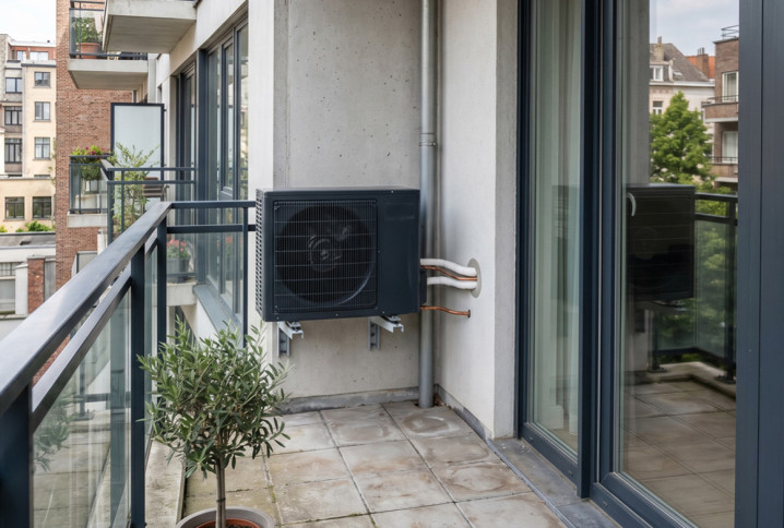 Unité extérieure de pompe à chaleur installée sur le balcon d’un appartement.