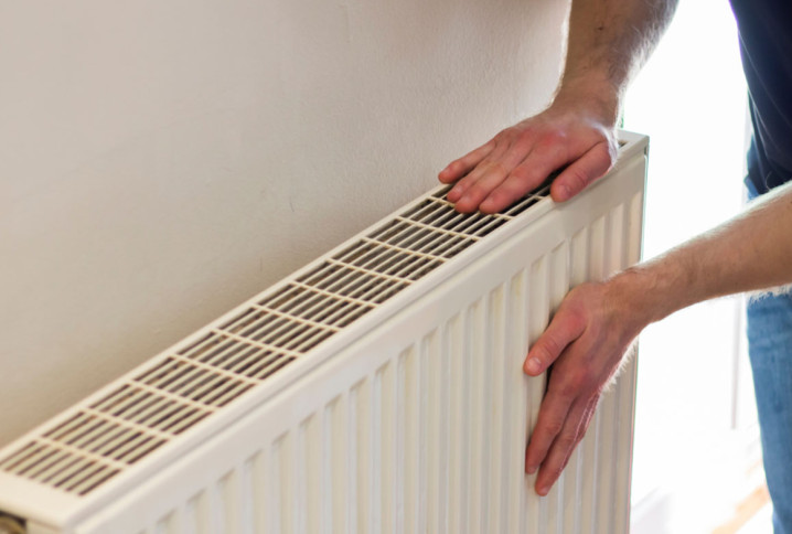 Homme qui touche le dessus et le flanc de son radiateur pour ressentir la température