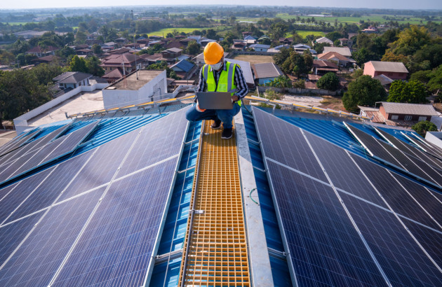 Ouvrier sur un toit qui utilise un ordinateur pour calculer le rendement d'une installation solaire