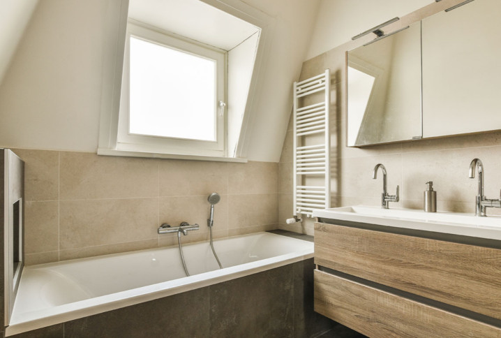 Salle de bains sous combles avec baignoire et meuble double vasque.