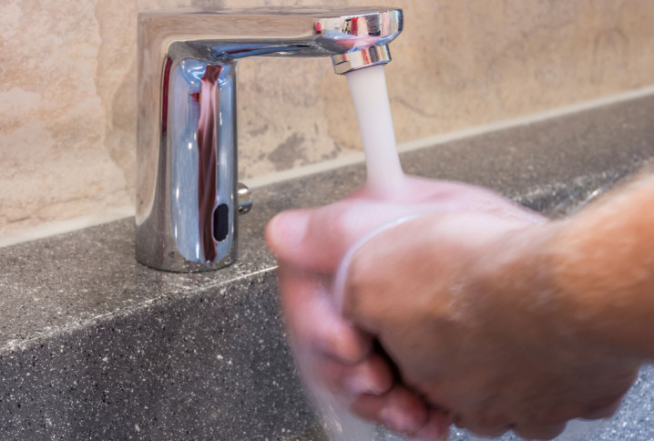 Homme qui se lave les mains en utilisant un robinet infrarouge