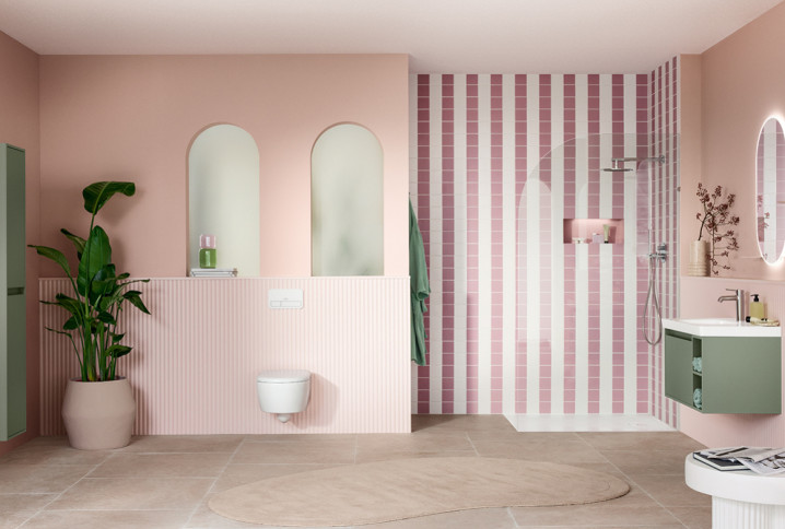 Salle de bains contemporaine aux tons rose poudré et vert sauge, avec douche ouverte, WC suspendu et meuble vasque compact.