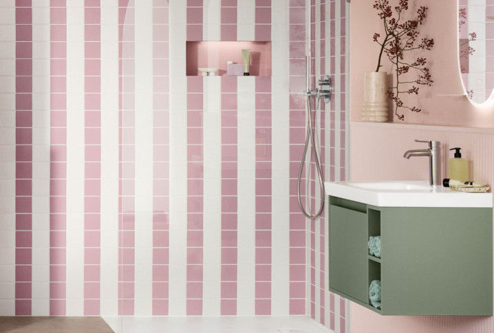 Salle de bains colorée avec douche à l’italienne habillée de carreaux roses et blancs et meuble vasque vert sauge suspendu.
