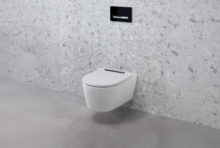 WC suspendu blanc moderne sur un mur en carrelage effet terrazzo gris clair dans une toilette design.