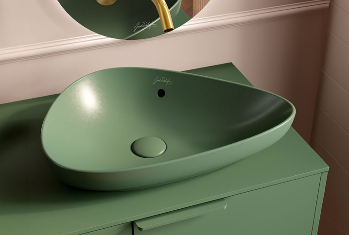 Vasque à poser verte mate au design organique installée sur un meuble coordonné.
