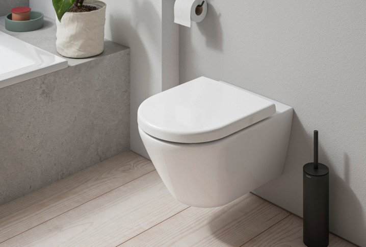 WC suspendu caréné blanc avec brosse WC noire, ambiance salle de bains moderne.