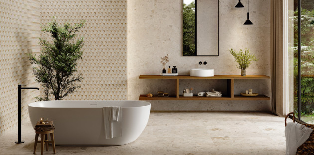 Salle de bains naturelle avec baignoire îlot blanche, vasque à poser et carrelage mural décoratif en relief.