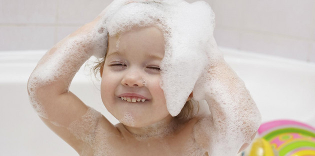 Enfant se lavant les cheveux dans une baignoire