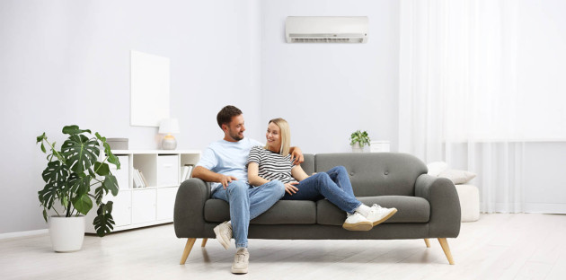 Couple installé dans un salon moderne avec climatisation réversible murale, confort thermique au quotidien