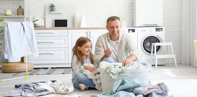 Homme et sa fille qui sont très heureux de mettre du linge dans le panier de linge