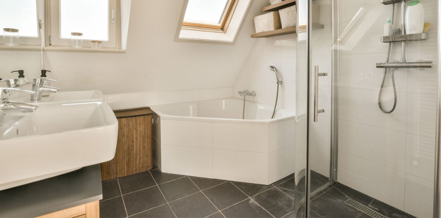 Baignoire d'angle blanche dans une salle de bains aménagée sous les combles