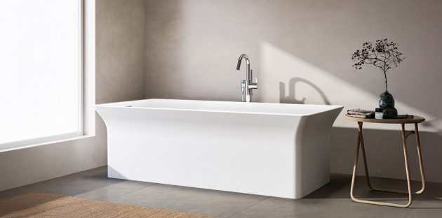 Baignoire îlot rectangulaire au design minimaliste installée dans une salle de bains contemporaine aux tons doux et naturels.