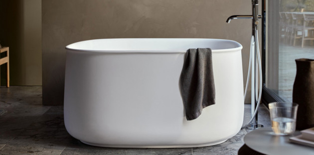 Baignoire îlot blanche aux lignes arrondies installée dans une salle de bains contemporaine.