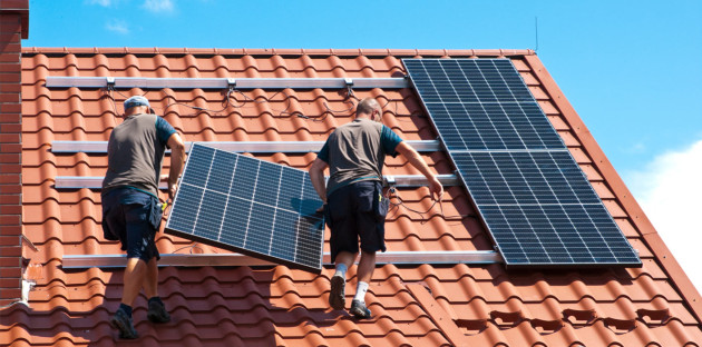 Deux personnes qui installent un panneau solaire sur un toît