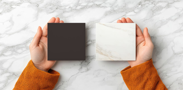 Femme qui tient des carreaux de carrelage dans ses mains, un carreaux noir et un carreau blanc