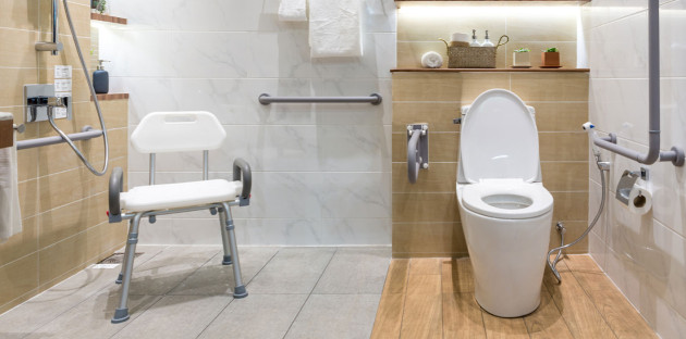 salle de bains accessible aux PMR avec toilettes et barre d'appui avec carrelage antidérapant au sol et siège de douche sécurisé