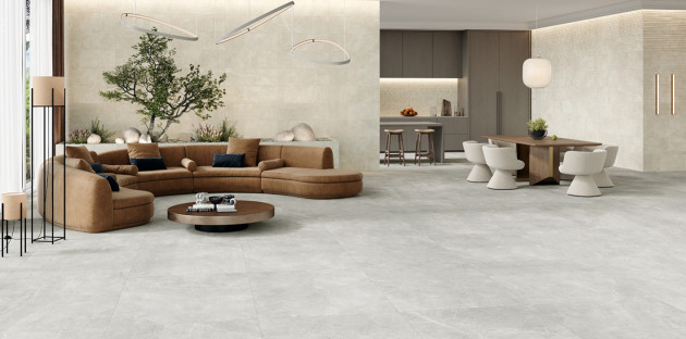 Grand salon contemporain avec carrelage effet pierre claire grand format et espace de vie ouvert chaleureux.