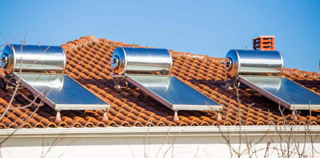 Trois panneaux solaires thermiques avec réservoir qui sont installés sur un toit de maison