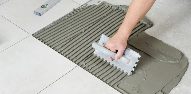 Homme qui utilise un peigne pour poser des carreaux de carrelage