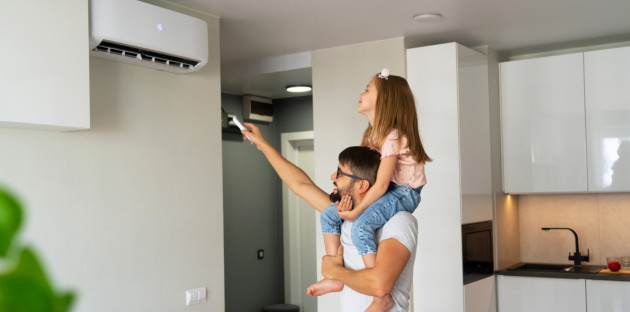 Famille réglant une climatisation murale dans un salon moderne.