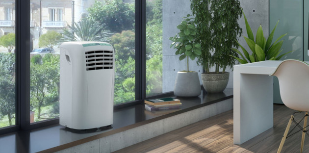 Climatiseur mobile blanc installé près d’une baie vitrée dans un intérieur moderne et lumineux.