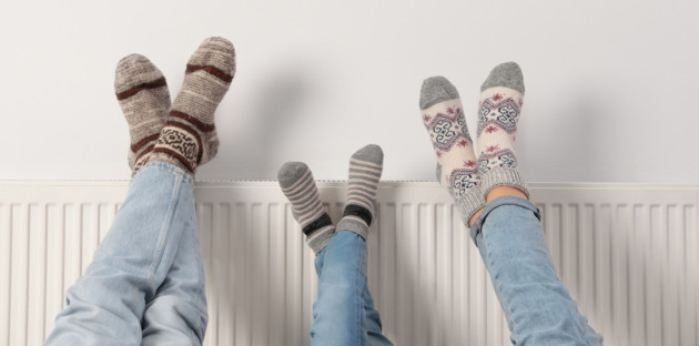 personnes qui chauffent leurs pieds au dessus du radiateur