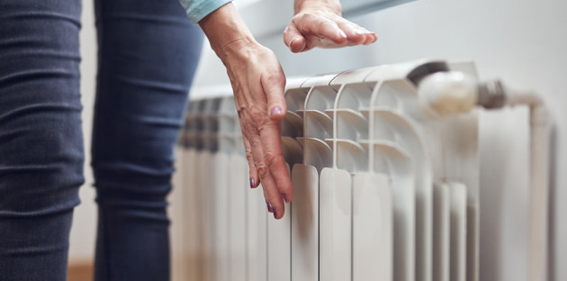 Femme qui met ses mains proche d'un radiateur pour sentir la chaleur