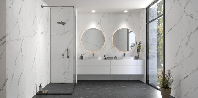 Salle de bains moderne avec douche à l’italienne, double vasque suspendue et grands carreaux effet marbre blanc.
