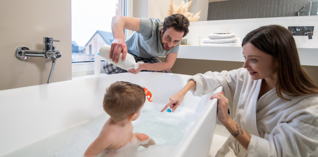 Jeune famille qui passe du bon temps dans sa salle de bains et avec la baignoire